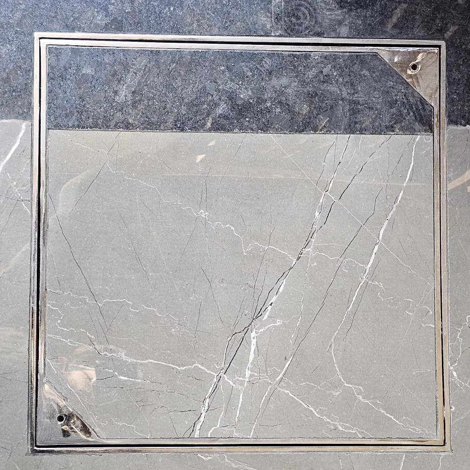 Recessed stainless steel chamber cover installed in marble flooring